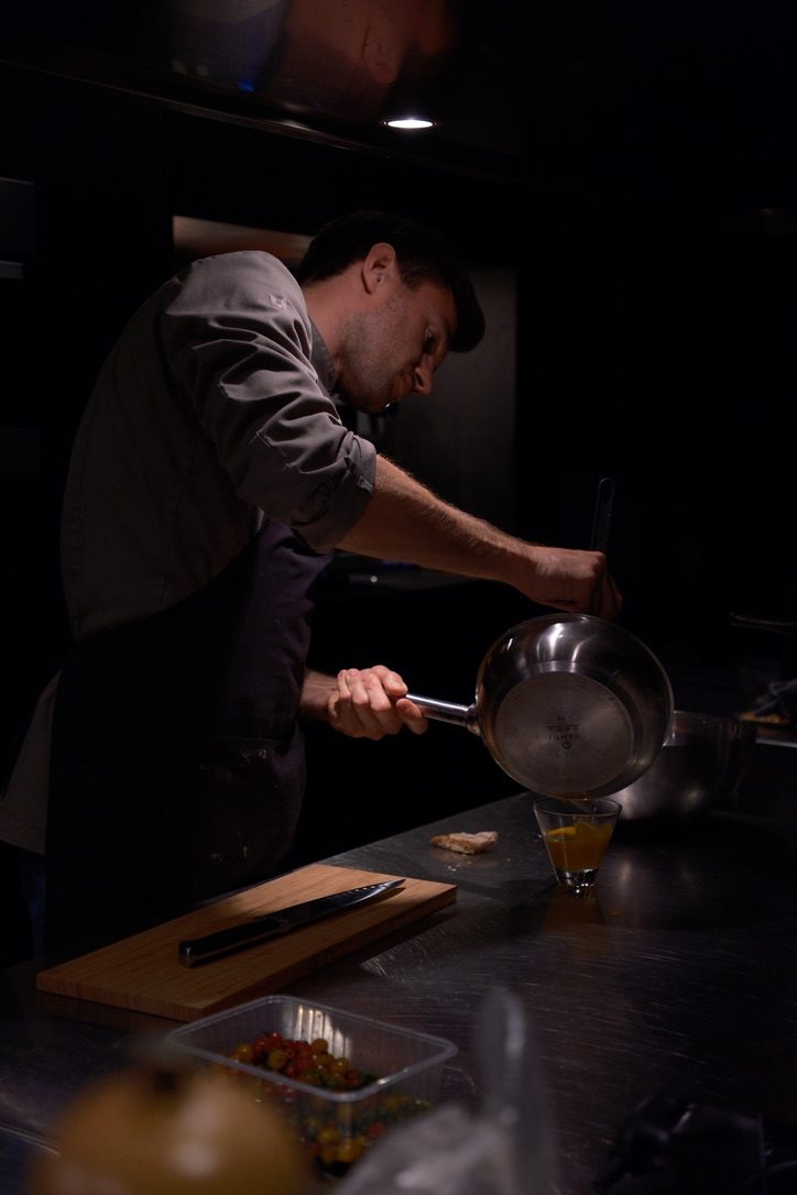Chef schenkt een saus in een glas in een open keuken