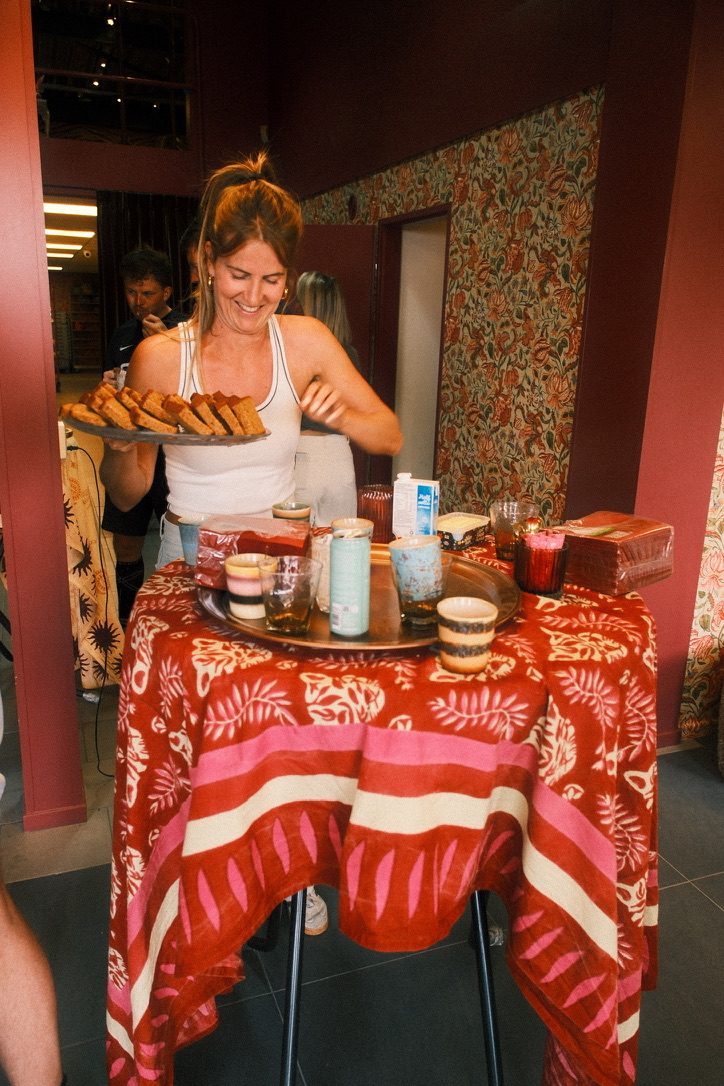 Vrouw serveert ontbijt op een tafel met rood kleed